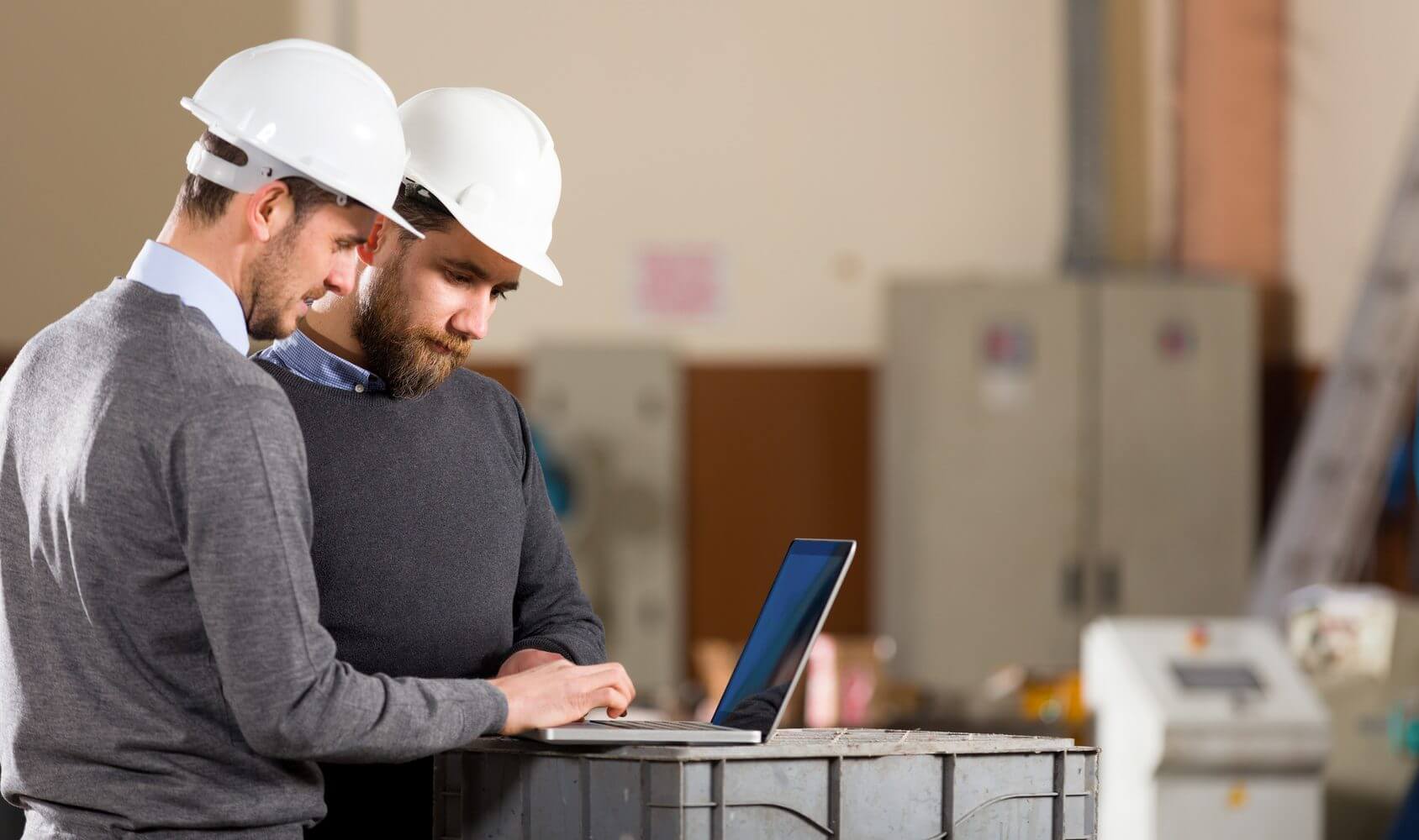 Two businessman working with laptop in factory